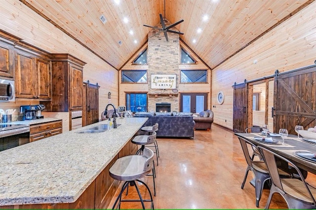 kitchen featuring wood ceiling, sink, a barn door, and light stone counters