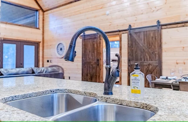 kitchen with sink, lofted ceiling, and wood walls