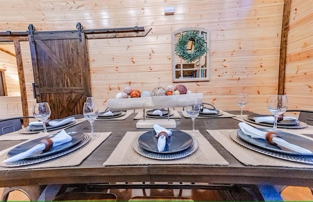 dining space featuring wooden walls and a barn door