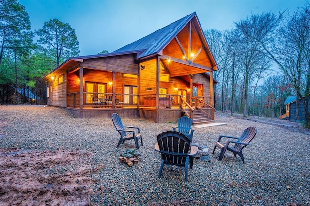 back house at dusk with covered porch and an outdoor fire pit