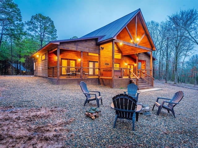 back house at dusk featuring covered porch and a fire pit