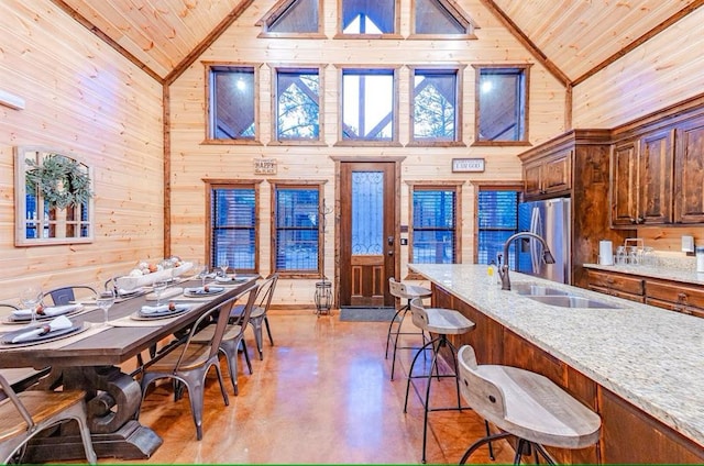 dining room featuring high vaulted ceiling, wooden walls, wood ceiling, and sink