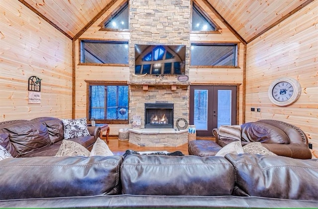 living room with french doors, a stone fireplace, wooden ceiling, high vaulted ceiling, and wooden walls