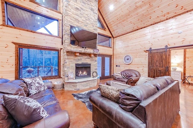 living room with a fireplace, a barn door, high vaulted ceiling, and wooden walls