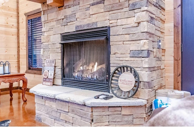 details with an outdoor stone fireplace, concrete flooring, and wood walls