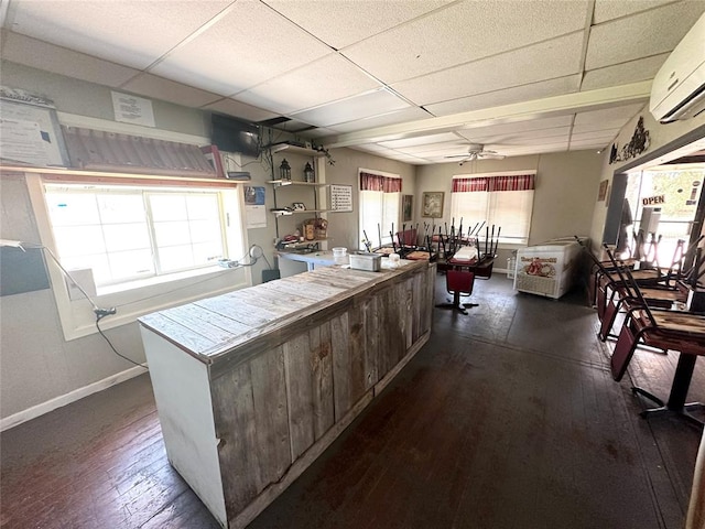 kitchen featuring ceiling fan, a healthy amount of sunlight, dark hardwood / wood-style floors, and a wall unit AC