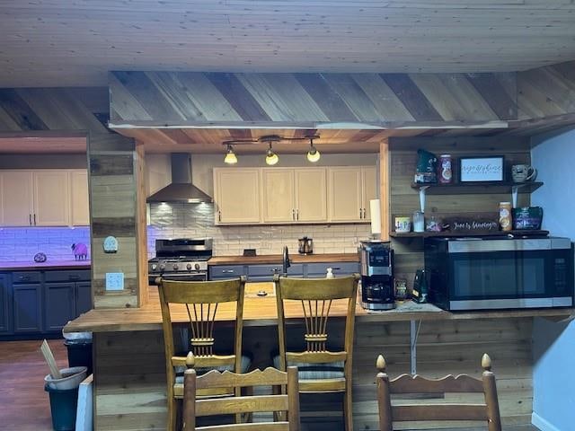 kitchen with decorative backsplash, appliances with stainless steel finishes, white cabinetry, and wall chimney exhaust hood