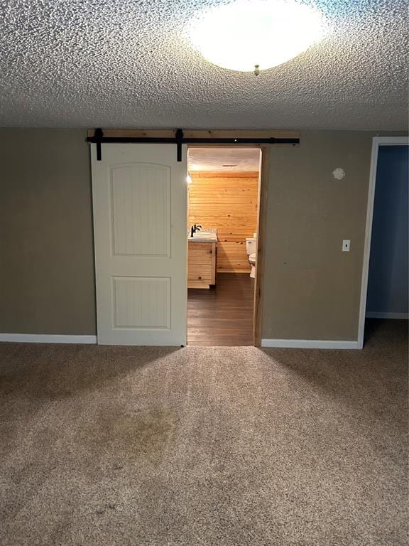 carpeted spare room with a textured ceiling and a barn door