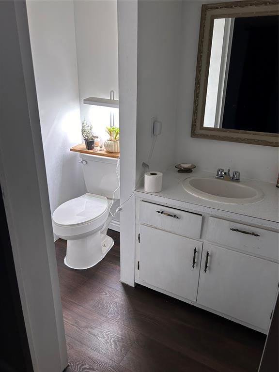 bathroom with hardwood / wood-style floors, vanity, and toilet