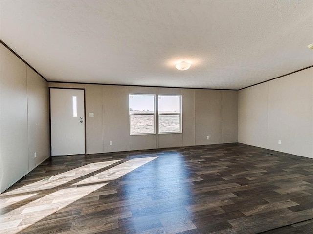 unfurnished room with dark wood-type flooring, crown molding, and a textured ceiling