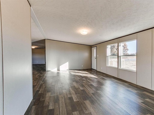 spare room featuring dark hardwood / wood-style floors and a textured ceiling