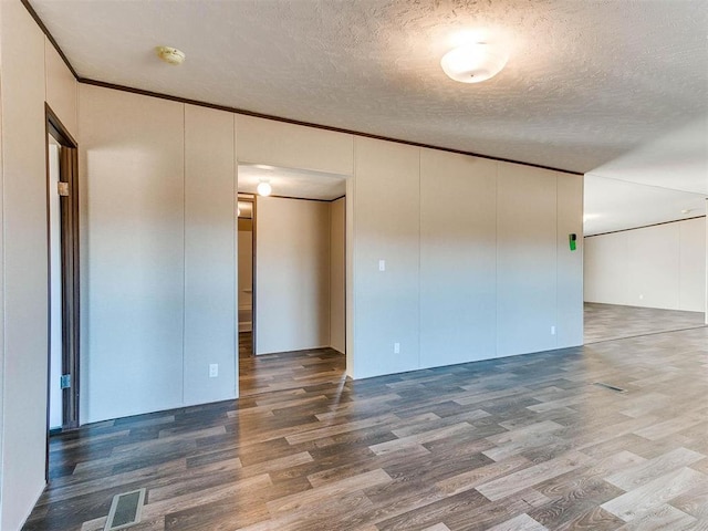 spare room with crown molding, wood-type flooring, and a textured ceiling