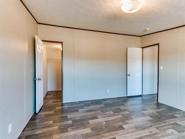 spare room featuring crown molding, dark hardwood / wood-style flooring, and a textured ceiling