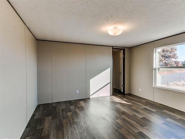 spare room featuring a textured ceiling and dark hardwood / wood-style flooring