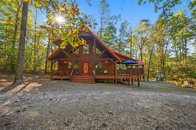 66 Lost Oaks Trl, Broken Bow, OK 74728 - view of front facade featuring log veneer siding, a chimney, and a deck
