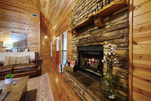 living room with high vaulted ceiling, wood-type flooring, wooden walls, a fireplace, and wood ceiling