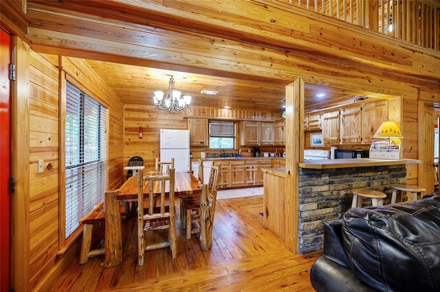 66 Lost Oaks Trl, Broken Bow, OK 74728 - dining area with a chandelier, wood walls, and light wood-style flooring