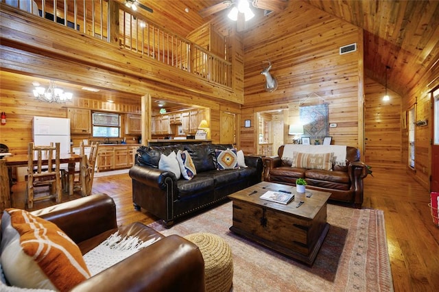 living room with wood walls, light hardwood / wood-style flooring, and high vaulted ceiling