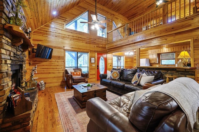 66 Lost Oaks Trl, Broken Bow, OK 74728 - living area featuring a ceiling fan, wood walls, wooden ceiling, a stone fireplace, and high vaulted ceiling