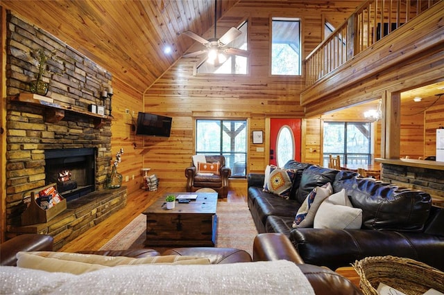 66 Lost Oaks Trl, Broken Bow, OK 74728 - living room with high vaulted ceiling, wood finished floors, wooden walls, a fireplace, and a ceiling fan
