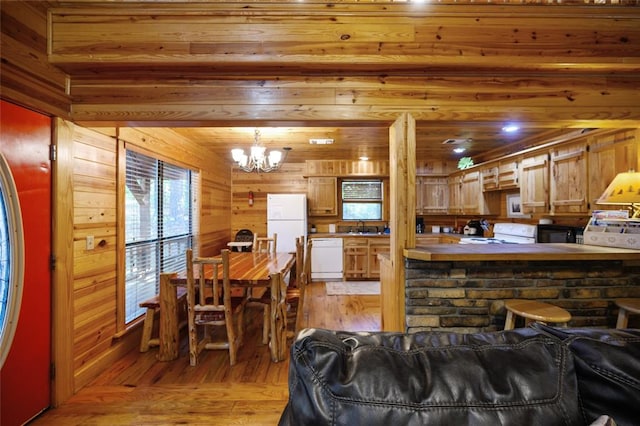 living room with wooden walls, light hardwood / wood-style flooring, a notable chandelier, and sink