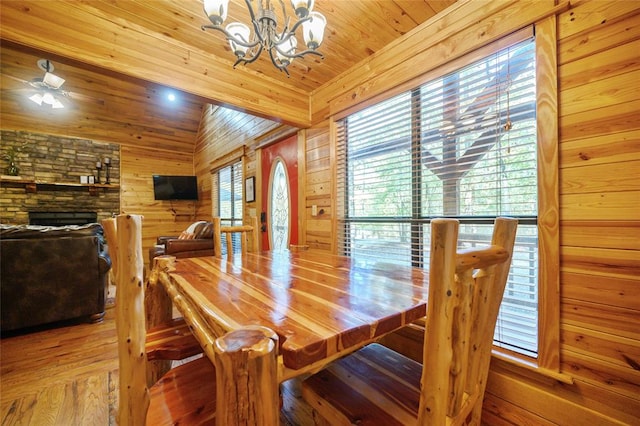 dining room with hardwood / wood-style floors, vaulted ceiling, wooden walls, wood ceiling, and ceiling fan with notable chandelier