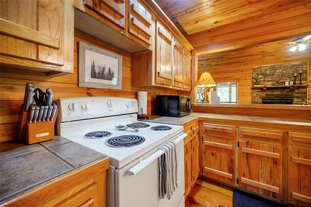 kitchen with wood ceiling, ceiling fan, wooden walls, electric stove, and a fireplace