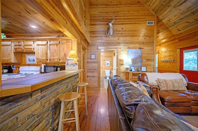 living room with wood walls, high vaulted ceiling, dark wood-type flooring, and wooden ceiling