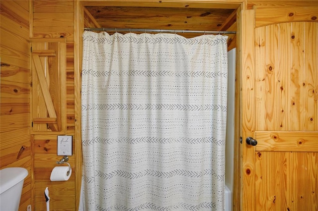 bathroom featuring wood walls and toilet