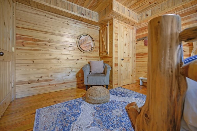 living area with wooden walls, light hardwood / wood-style flooring, and wooden ceiling