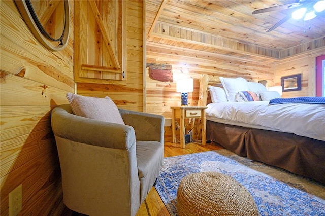 bedroom featuring ceiling fan, hardwood / wood-style floors, wood ceiling, and wood walls