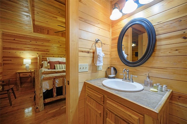 bathroom with hardwood / wood-style floors, vanity, and wooden walls