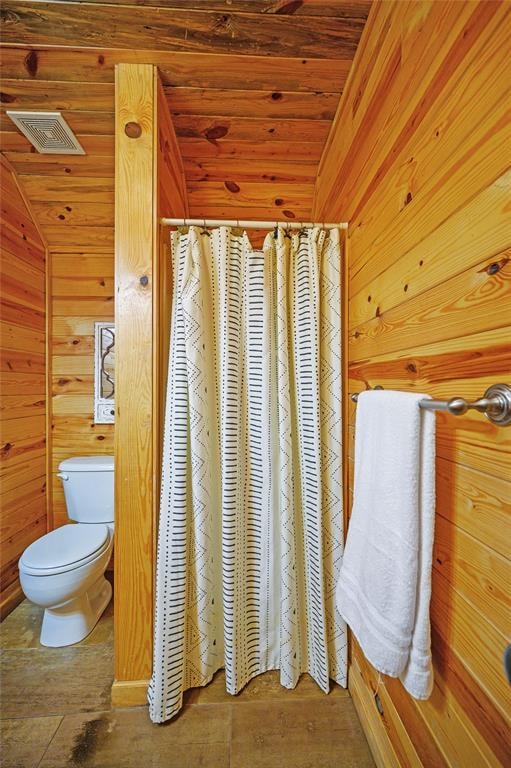 bathroom featuring toilet, vaulted ceiling, wooden walls, and wood ceiling