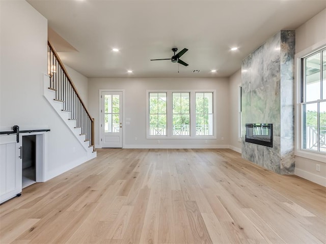 unfurnished living room with a fireplace, light wood-type flooring, and a wealth of natural light