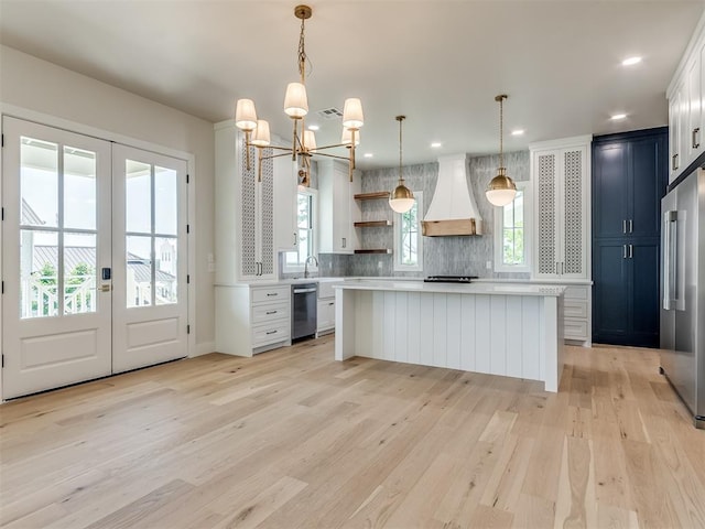 kitchen featuring a wealth of natural light, stainless steel appliances, hanging light fixtures, and custom exhaust hood