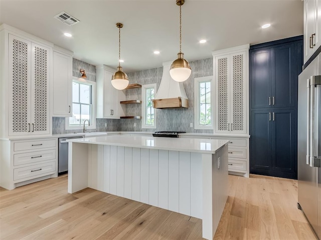 kitchen featuring decorative light fixtures, stainless steel dishwasher, plenty of natural light, and premium range hood