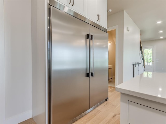 kitchen featuring white cabinets, light wood-type flooring, and stainless steel built in fridge