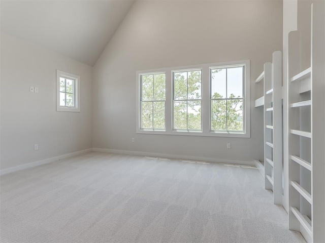 carpeted spare room featuring high vaulted ceiling