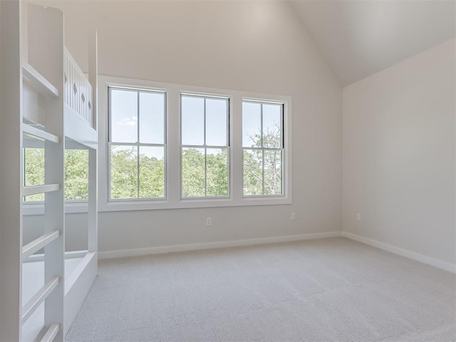 spare room with plenty of natural light, high vaulted ceiling, and light colored carpet