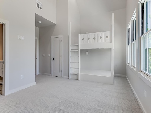 unfurnished bedroom with light carpet and a high ceiling