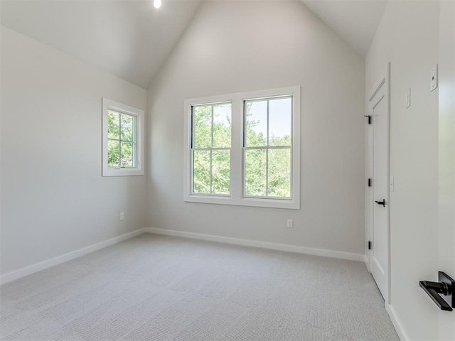 carpeted spare room featuring high vaulted ceiling