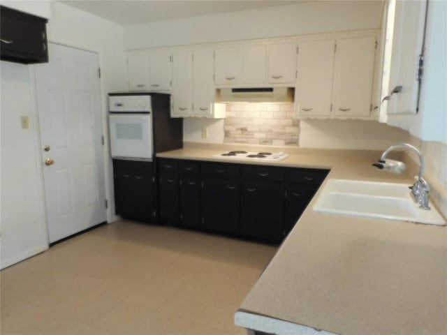 kitchen featuring range hood, sink, white cabinets, and white appliances