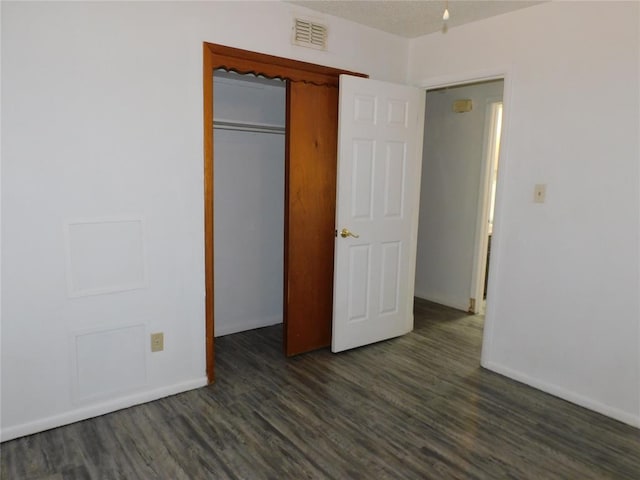 unfurnished bedroom with dark hardwood / wood-style flooring and a closet