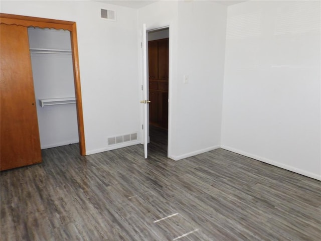 unfurnished bedroom with dark hardwood / wood-style flooring and a closet