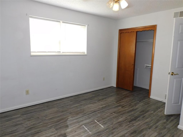 unfurnished bedroom featuring ceiling fan, dark hardwood / wood-style flooring, a textured ceiling, and a closet