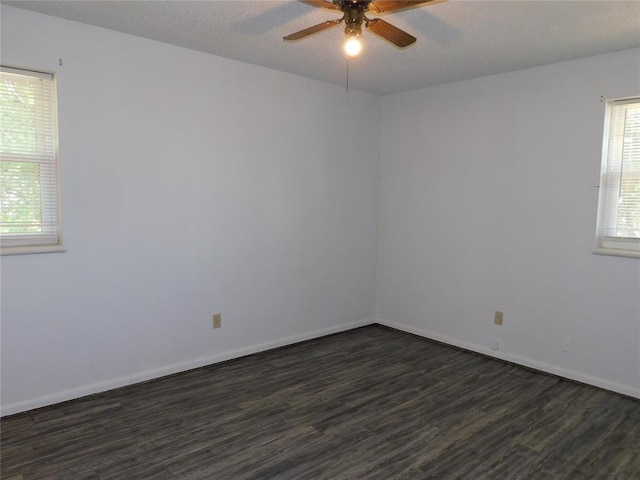 spare room featuring a textured ceiling, a wealth of natural light, dark wood-type flooring, and ceiling fan