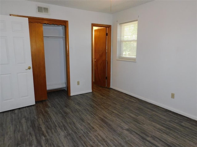 unfurnished bedroom featuring dark hardwood / wood-style floors and a closet