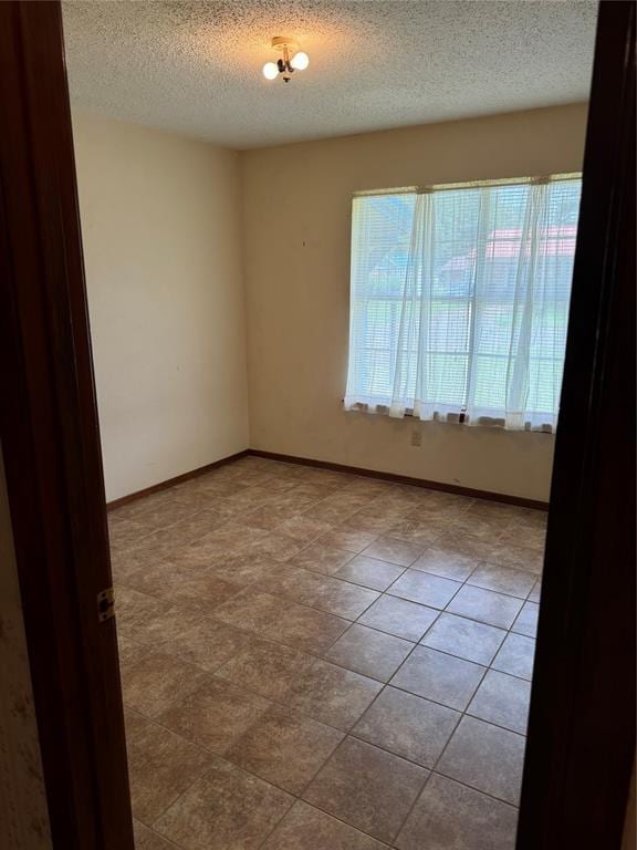 unfurnished room with light tile patterned floors and a textured ceiling