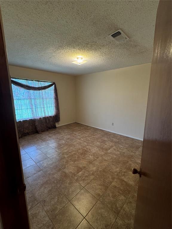 spare room with a textured ceiling and tile patterned floors