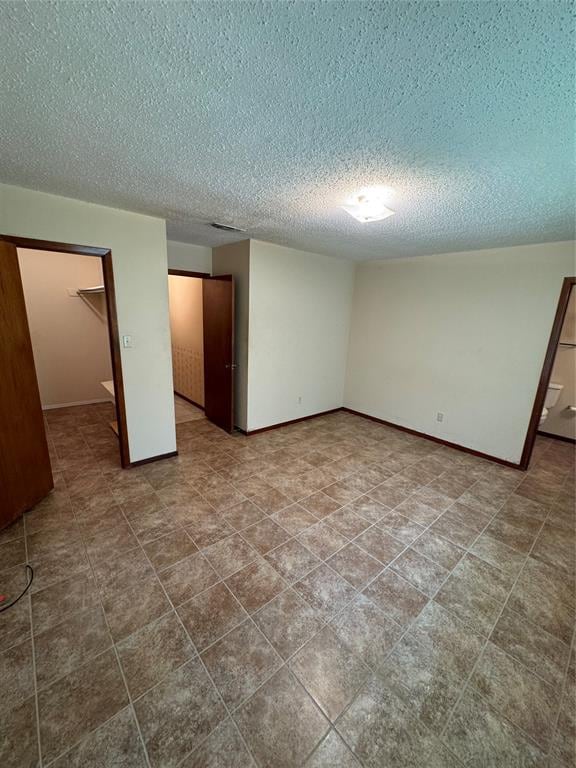 unfurnished bedroom with a walk in closet, a textured ceiling, and a closet